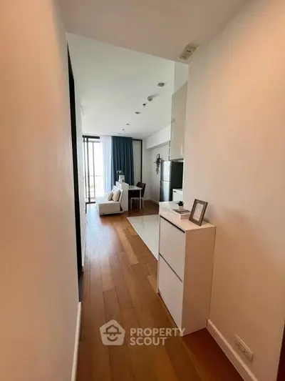 Modern apartment hallway leading to a bright living area with wooden flooring and stylish decor.