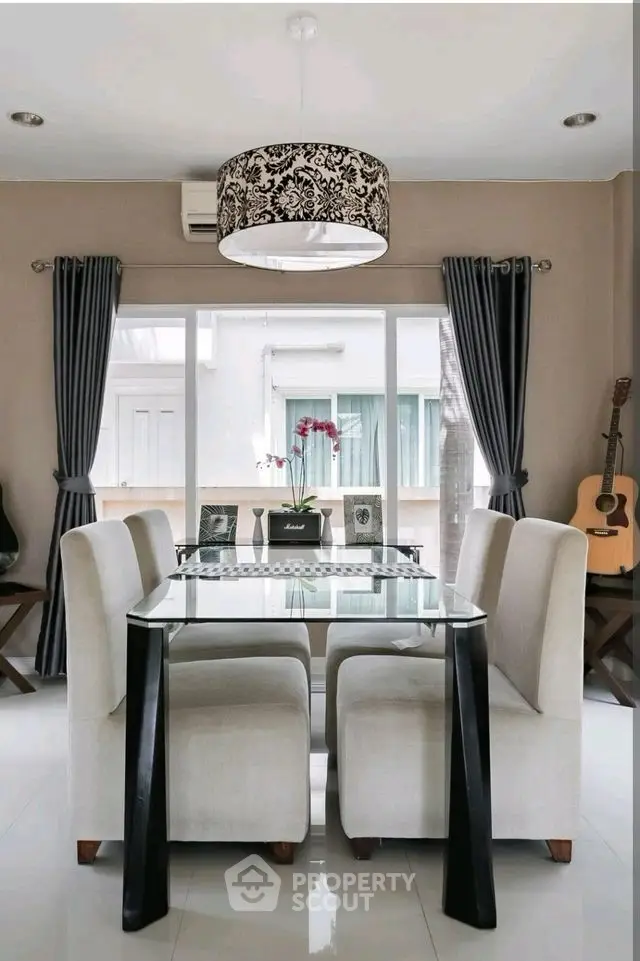 Elegant dining room with modern glass table and plush chairs, featuring stylish decor and natural light.