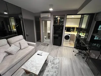 Modern living room with sleek design, featuring a cozy sofa, marble coffee table, and open kitchen with appliances.