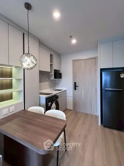 Modern kitchen with sleek appliances and stylish dining area in a contemporary apartment.