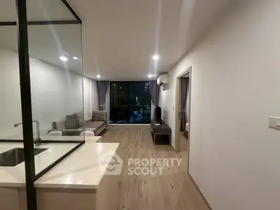 Modern living room with open layout and sleek design, featuring a cozy sofa and large windows.