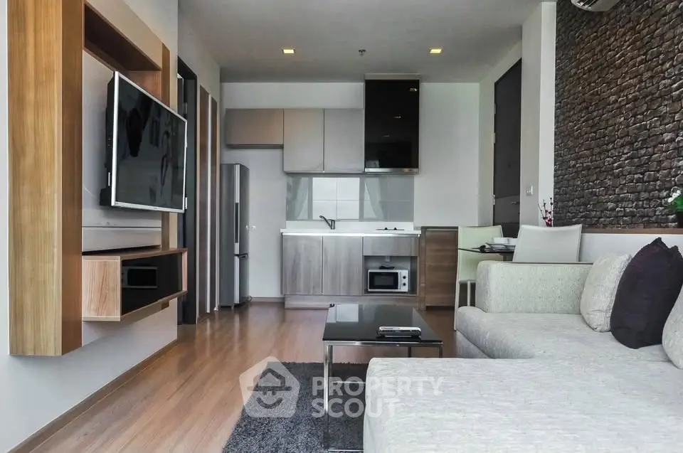 Modern living room with open kitchen, sleek furniture, and wall-mounted TV in stylish apartment.