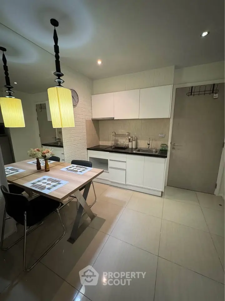 Modern kitchen with dining area, sleek cabinetry, and stylish lighting in a contemporary apartment.