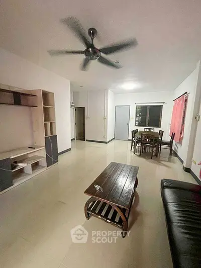 Spacious living room with modern furniture and ceiling fan, perfect for family gatherings.