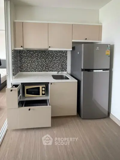 Modern compact kitchen with sleek cabinetry and stainless steel fridge