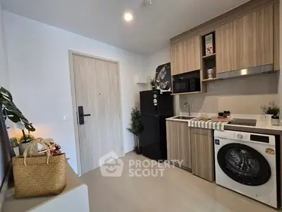 Modern compact kitchen with wooden cabinets, washing machine, and sleek appliances in a cozy apartment.