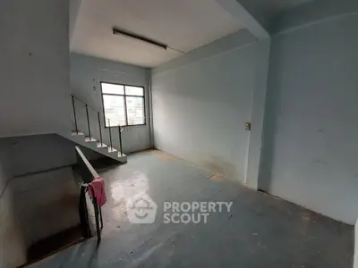 Spacious interior with staircase and large window, ideal for renovation.