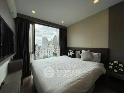 Modern bedroom with city view, featuring cozy bedding and stylish decor in a high-rise apartment.