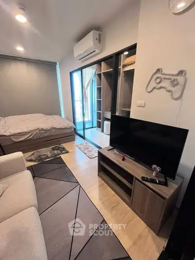 Modern studio apartment with cozy bedroom and stylish living area, featuring a sleek TV setup and air conditioning.