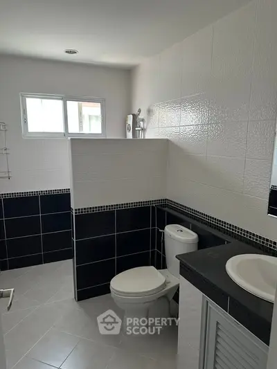 Modern bathroom with sleek black and white tiles and natural light.