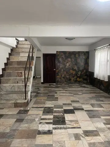 Spacious interior with unique stone tile flooring and staircase, ideal for modern living.