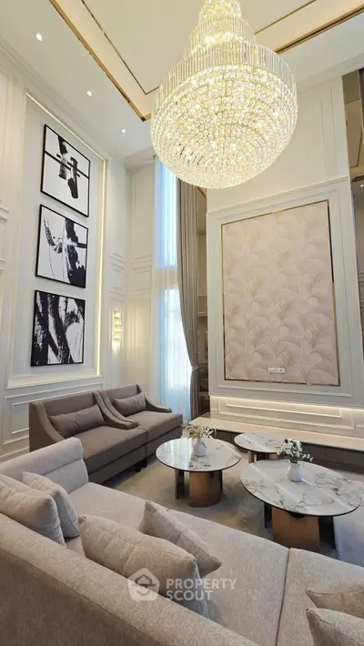 Luxurious living room with high ceiling, elegant chandelier, and modern decor