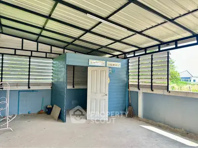 Spacious covered outdoor area with open walls and a storage room