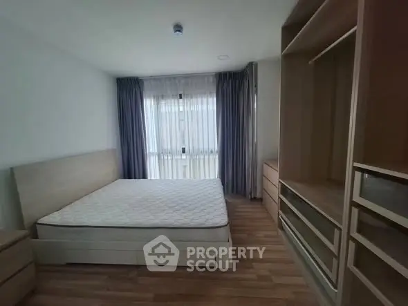 Spacious bedroom with large window and ample storage in modern apartment
