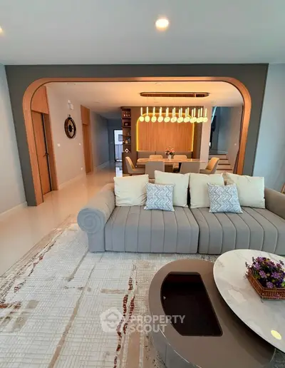 Luxurious living room with elegant sofa and modern dining area in open layout.