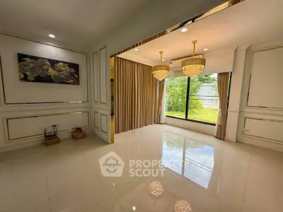 Elegant living room with large windows and chandeliers, overlooking a lush garden.