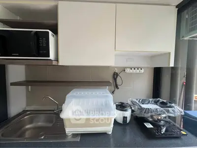 Modern kitchen with sleek appliances and ample counter space, featuring a microwave, rice cooker, and induction stove.