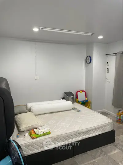 Cozy bedroom with simple decor and children's play area, perfect for a small family.