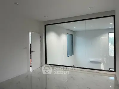 Spacious modern room with large interior window and marble flooring
