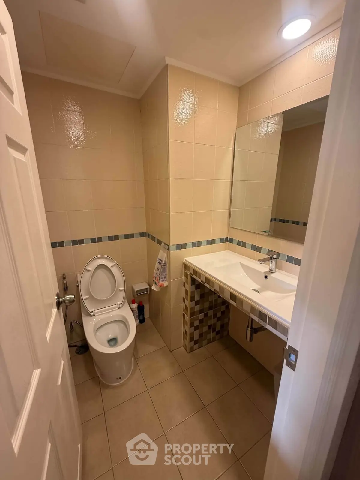 Compact bathroom with modern fixtures and tiled walls, featuring a sleek sink and toilet.
