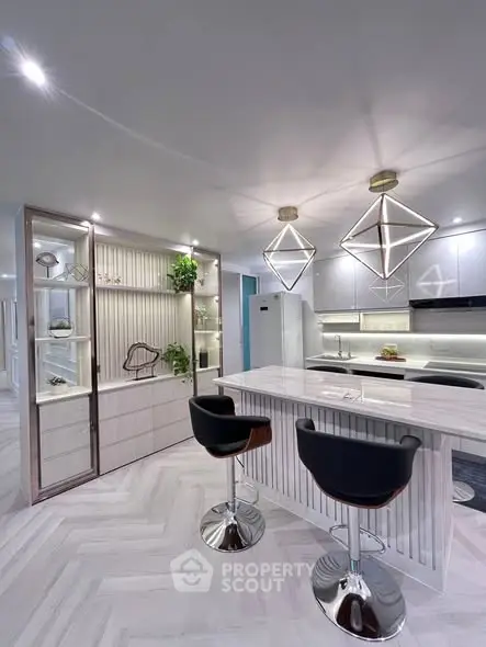 Modern kitchen with sleek design, featuring island seating and geometric pendant lights.
