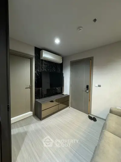 Modern living room with sleek TV setup and air conditioning in a stylish apartment.