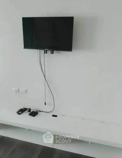 Modern minimalist living room with wall-mounted TV and sleek white console.