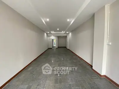 Spacious empty room with modern lighting and tiled flooring, ideal for customization.