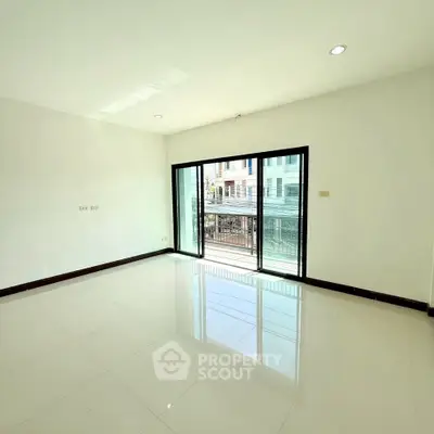 Bright empty room with large windows and balcony access in modern apartment.