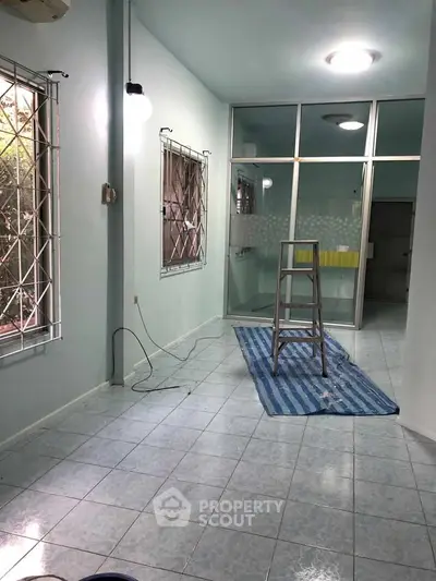 Spacious room with tiled floor and large windows, ideal for renovation or customization.