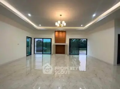 Spacious modern living room with elegant chandelier and large windows offering natural light.