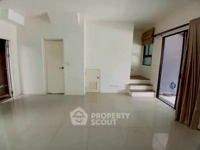 Spacious living room with modern tile flooring and natural light from large windows.