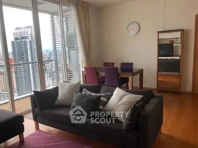 Spacious living room with city view and modern decor in high-rise apartment.