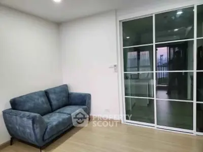 Modern living room with stylish blue sofa and sliding glass doors leading to balcony.