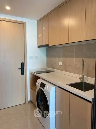 Modern kitchen with built-in cabinets and washing machine in sleek apartment.