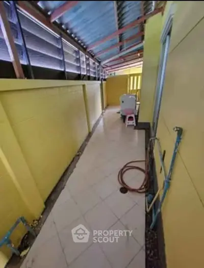 Charming yellow exterior corridor with tiled floor and washing machine setup.