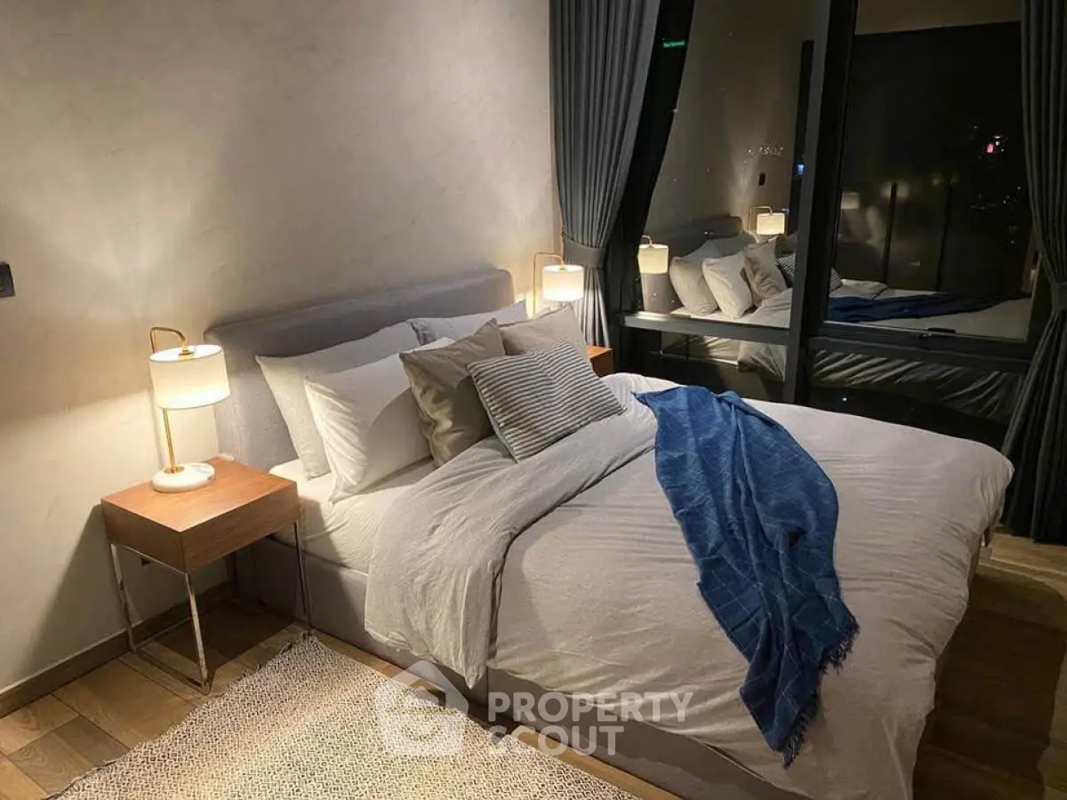 Modern bedroom with cozy lighting and stylish decor, featuring a large bed and elegant curtains.