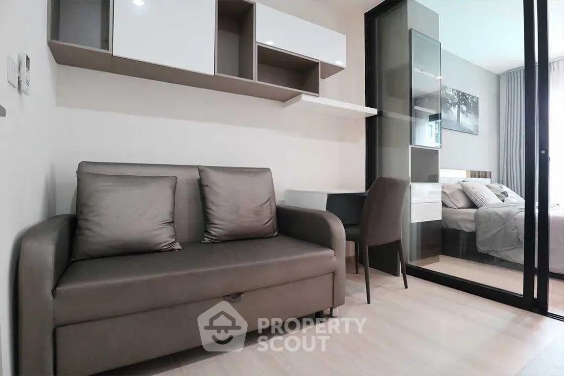 Modern studio apartment with sleek furniture and glass partitioned bedroom.