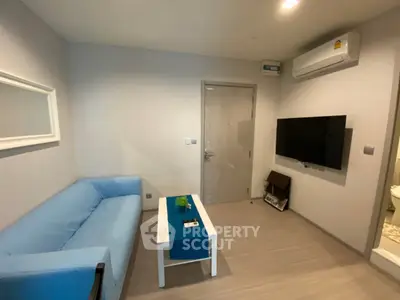Modern living room with blue sofa, wall-mounted TV, and air conditioning unit.