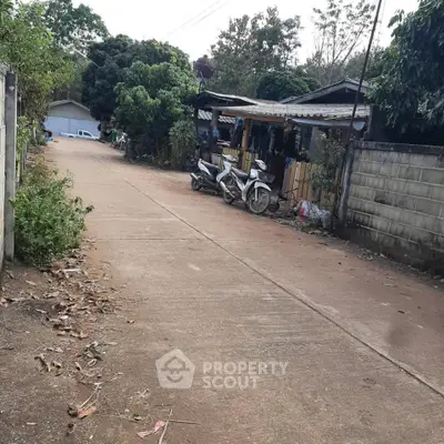 Charming rural street view with lush greenery and rustic homes, perfect for serene living.