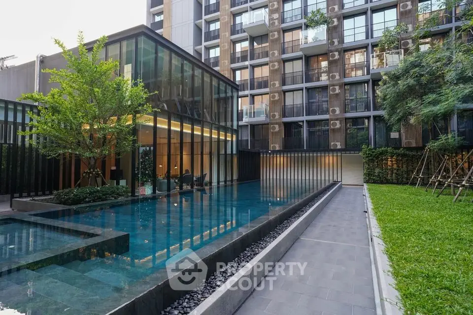 Modern apartment building with sleek pool and lush garden area.