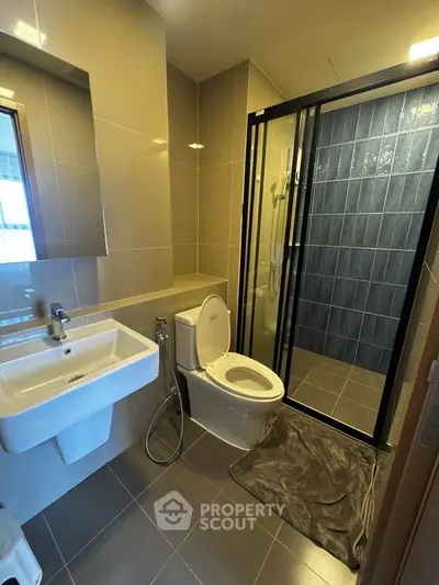 Modern bathroom with sleek design, featuring a glass shower enclosure and contemporary fixtures.