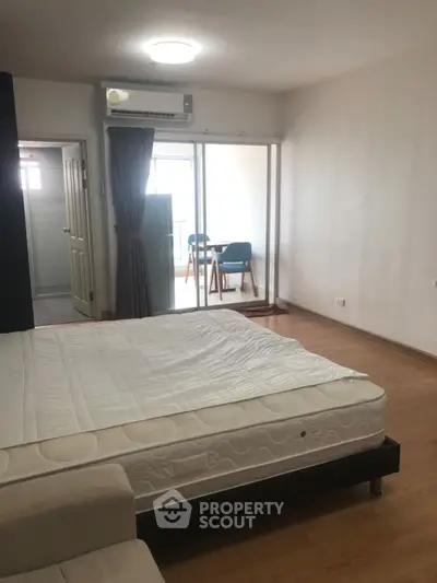 Spacious bedroom with balcony access and natural light in modern apartment.