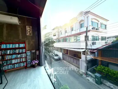 Modern living room with large window showcasing urban street view and stylish interior decor.
