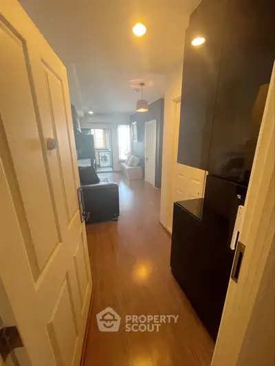 Modern apartment entrance leading to a cozy living room with wooden flooring and stylish decor.