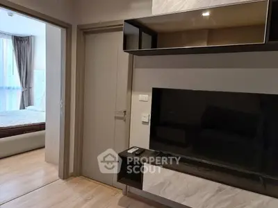 Modern living room with sleek TV unit and view into a cozy bedroom