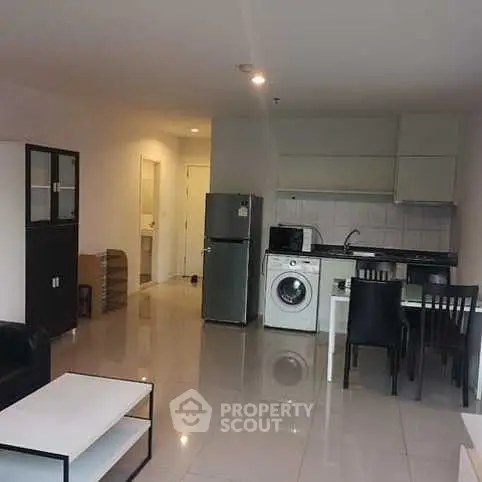 Modern open-plan living room with kitchen, dining area, and appliances in a cozy apartment.