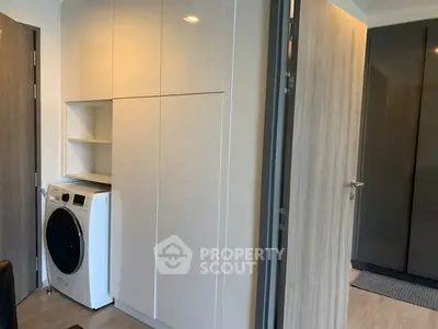 Modern laundry area with sleek cabinetry and washing machine in compact space.