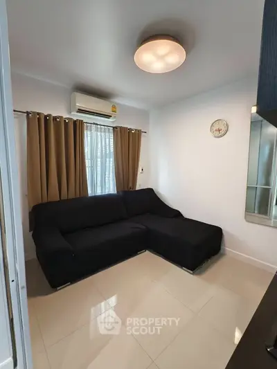 Modern living room with sleek black sofa, air conditioning, and elegant curtains in a cozy apartment.