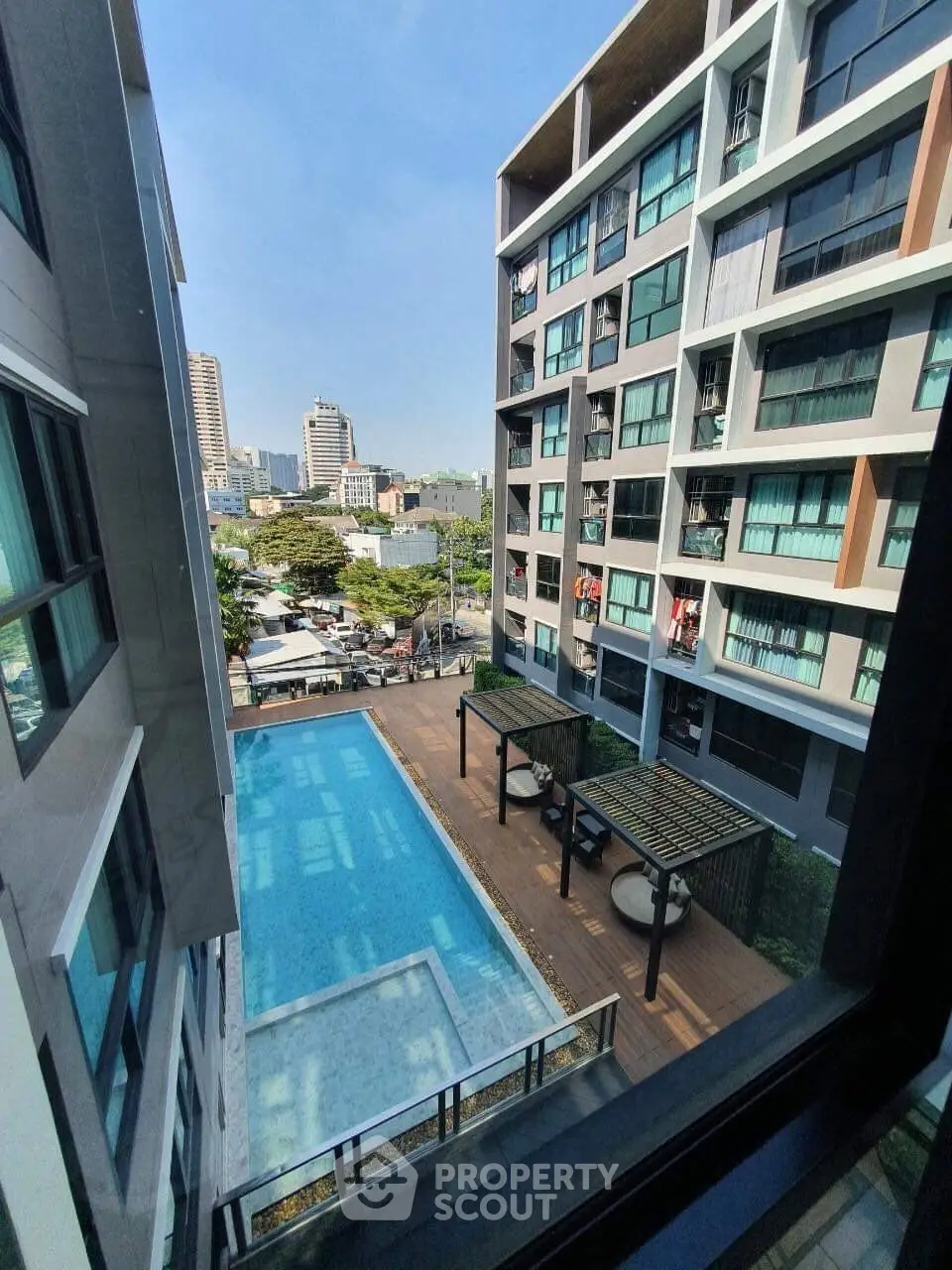 Modern apartment building with pool view and cityscape in the background.